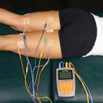 female has NMES applied to hamstrings to aid recovery.